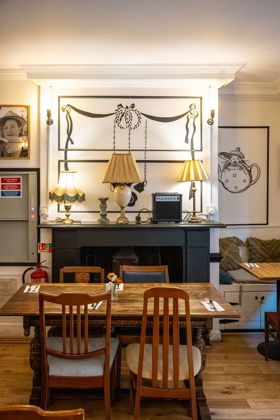 The back room with an old fireplace, brass lamps and wooden tables