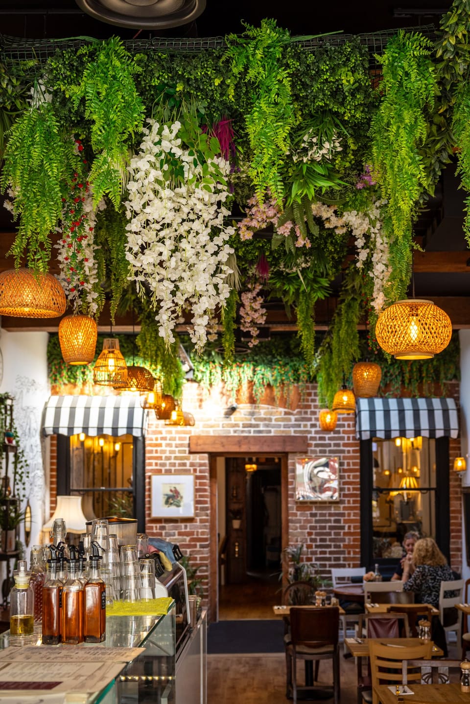 The counter under hanging greenery, rattan lanterns and a striped awning