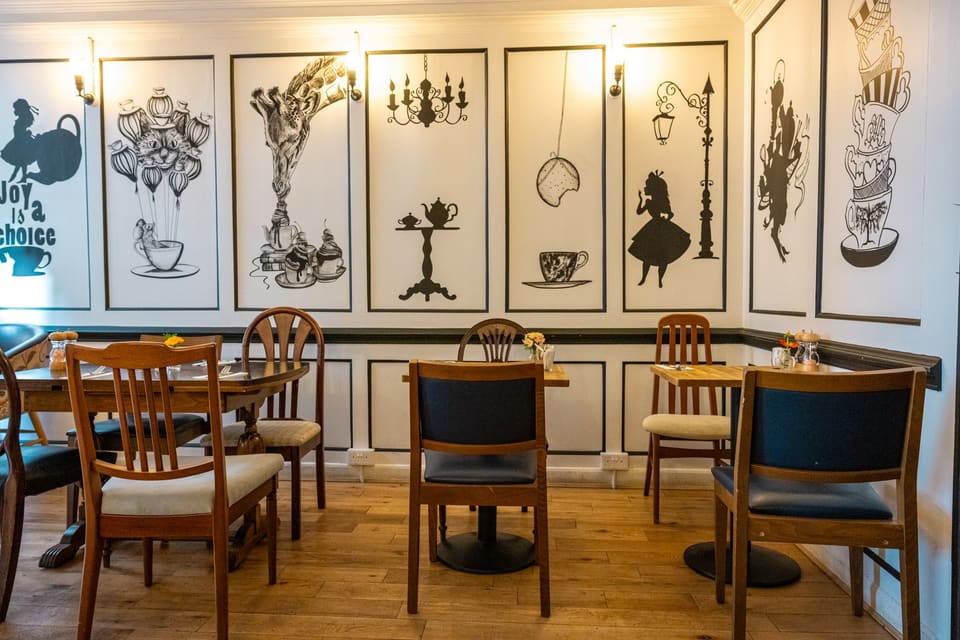 Dining room with black-and-white Wonderland murals of teapots, teacups and Alice above wooden tables