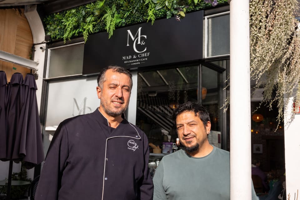 Two of the Mad & Chef team, one in a chef’s jacket, outside the restaurant under the M&C sign